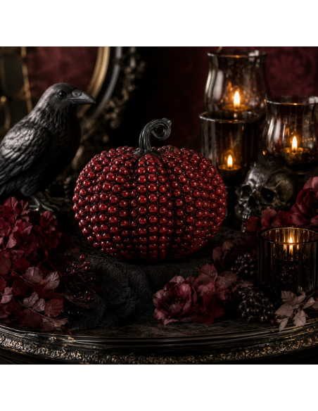 Citrouille rouge perlée dans une décoration Halloween chic avec chandeliers noirs